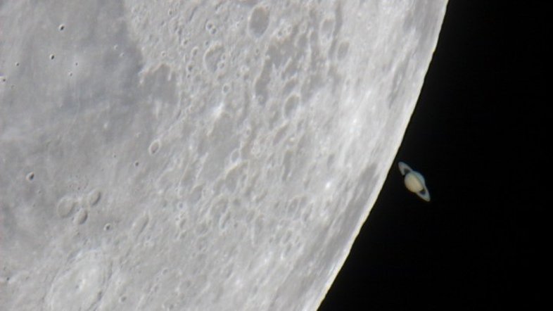 Em maio de 2007, poucos dias depois de partilhar o céu noturno ocidental com Vênus, a Lua passou por Saturno, ocultando temporariamente o planeta conhecido por seus anéis. Como a Lua e os planetas vagam pelo céu perto do plano da eclíptica, tais eventos de ocultação não são incomuns, embora sejam dramáticos em imagens telescópicas. Neste registro, feito no Observatório Weikersheim, no Sul da Alemanha, Saturno aparece emergindo de trás da Lua, dando a ilusão de que está próximo de sua borda. No entanto, a Lua está a apenas 400 mil quilômetros de distância, enquanto Saturno fica a 1,4 bilhões de quilômetros da Terra