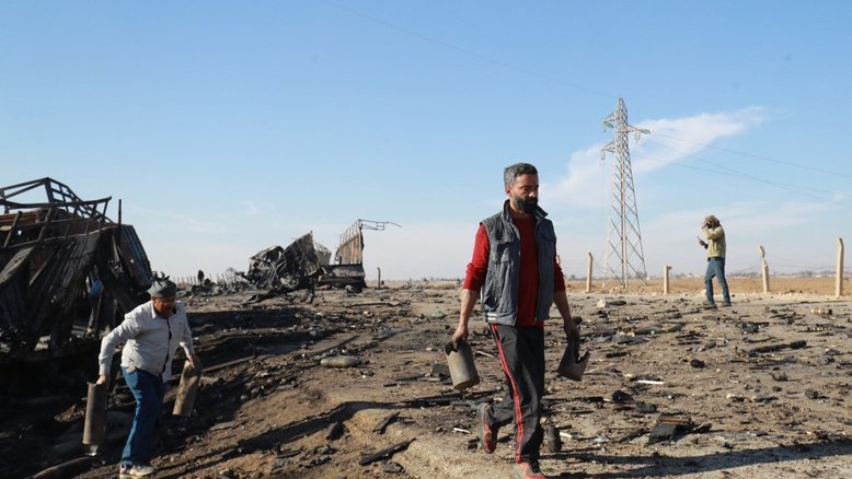 Pessoas pegam metal e munição não detonada do local do ataque aéreo israelense da noite anterior que teve como alvo carregamentos de armas que pertenciam às forças do governo sírio em Qamishli