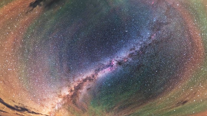 Este brilhante arco-íris com padrões repetitivos chama-se luminescência atmosférica. Nele, uma perturbação, como uma tempestade se aproximando, pode causar ondulações perceptíveis na atmosfera da Terra. Essas ondas gravitacionais são oscilações no ar análogas às criadas quando uma pedra é jogada em águas calmas. A luminescência atmosférica vermelha provavelmente se origina de moléculas de hidroxila, a cerca de 87 quilômetros de altitude, excitadas pela luz ultravioleta do Sol. A de cor laranja e verde, por sua vez, é causada por átomos de sódio e oxigênio um pouco mais acima. A paisagem desta imagem fica perto do Lago Keluke, na província de Qinghai, na China, exibindo a faixa central da Via Láctea como destaque