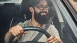 A modern bearded man driving a car