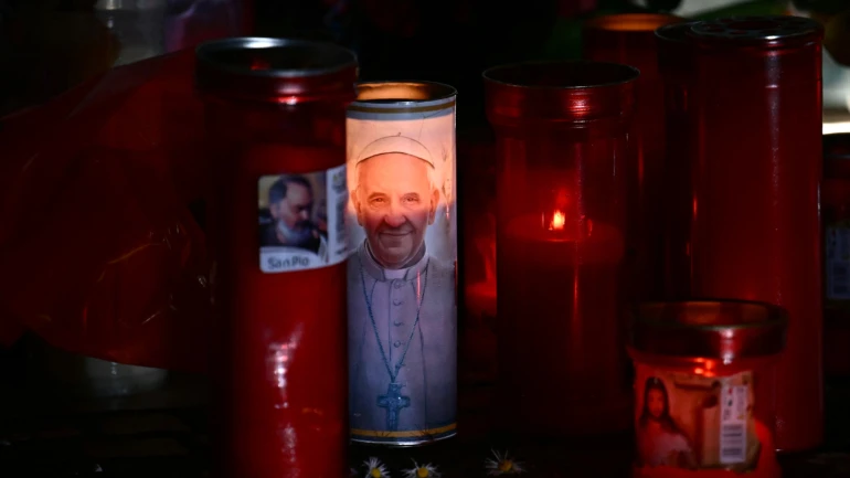 Velas são colocadas na estátua de João Paulo II do lado de fora do Hospital Universitário Gemelli, onde o Papa Francisco está hospitalizado com pneumonia, em Roma, em 03 de março de 2025. O Papa Francisco sofreu dois novos ataques respiratórios em 3 de março de 2025, disse o Vaticano, enquanto o pontífice de 88 anos luta para se recuperar da pneumonia