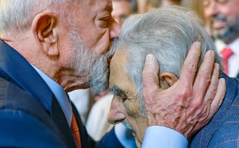 Lula beija a testa de José Mujica. Ambos tem os olhos fechados