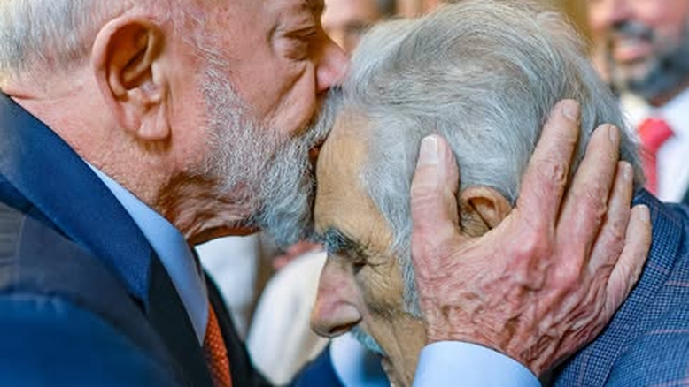 Lula beija a testa de José Mujica. Ambos tem os olhos fechados