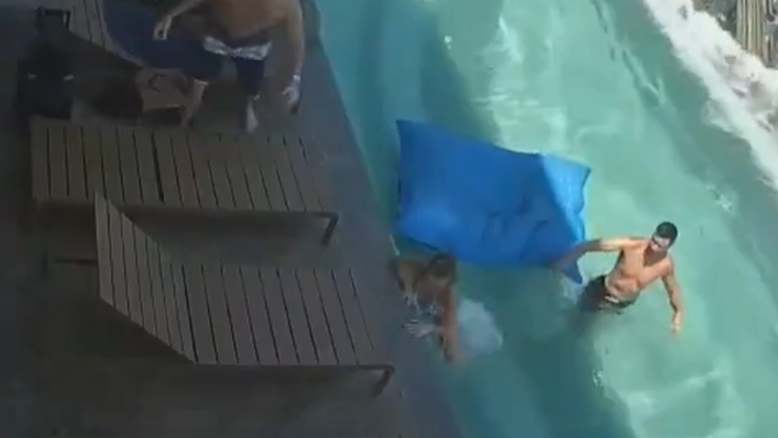 Frame do vídeo gravado por uma câmera de segurança durante o terremoto na Tailândia. Vemos as ondas fortes em uma piscina de borda infinita no topo de um prédio. Um casal tenta sair da água e um homem foge na borda