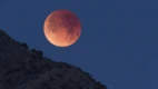 Nesta imagem, vê-se o registro de um Eclipse Lunar Total em janeiro de 2018, quando a Lua deslizou pela sombra do planeta Terra. Esta foto telescópica captura a Lua totalmente eclipsada, enquanto ela se punha acima do horizonte ocidental e das Montanhas Chiricahua do Sul, no Arizona. O tom avermelhado da Lua é devido à luz solar espalhada na sombra da Terra. Ainda assim, a sombra do planeta visivelmente fica mais escura perto do centro, em direção ao topo do disco lunar