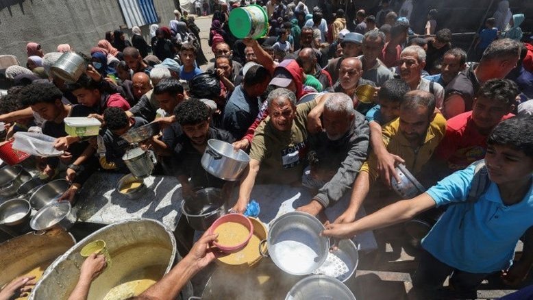 Palestinos fazem fila do lado de fora de uma cozinha solidária no campo de refugiados de Nuseirat, na Faixa de Gaza, em 26 de abril de 2025
