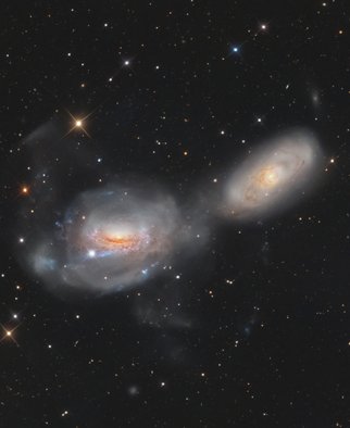 A galáxia espiral NGC 3169 parece estar se desenrolando como um novelo de lã cósmica. Ela fica a cerca de 70 milhões de anos-luz de distância, ao Sul da brilhante Regulus, a estrela Alfa da Constelação de Leão, e em direção à tênue Constelação do Sextante. Braços espirais retorcidos são estendidos em caudas de maré extensas à medida que NGC 3169 (esquerda) e a vizinha NGC 3166 interagem gravitacionalmente, fazendo com que as duas galáxias gradualmente se fundam em uma só. Arcos e plumas estelares alongados são indicações claras das interações gravitacionais em andamento