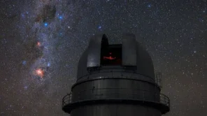 Nesta imagem, o telescópio do Observatório de La Silla do ESO, no Chile, admira o céu estrelado do Hemisfério Sul. O Cruzeiro do Sul — um dos asterismos mais característicos dessa região — pode ser visto à esquerda da cúpula aberta do telescópio, em meio ao plano da Via Láctea. A Constelação do Cruzeiro do Sul é bastante conhecida por este asterismo em forma de cruz, que compreende quatro estrelas: Alfa, Beta, Gama e Delta Crucis. A mais próxima dessas estrelas, Gama Crucis, situa-se a apenas 88 anos-luz da Terra, enquanto a mais distante está a 364 anos-luz. A estrela azul-esbranquiçada Alpha Crucis, o ponto mais baixo da Cruz, é a 13ª estrela mais brilhante em todo o céu noturno