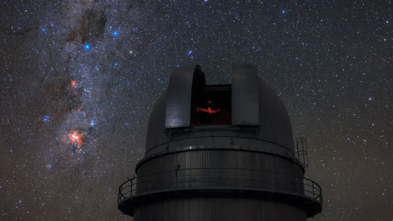 Nesta imagem, o telescópio do Observatório de La Silla do ESO, no Chile, admira o céu estrelado do Hemisfério Sul. O Cruzeiro do Sul — um dos asterismos mais característicos dessa região — pode ser visto à esquerda da cúpula aberta do telescópio, em meio ao plano da Via Láctea. A Constelação do Cruzeiro do Sul é bastante conhecida por este asterismo em forma de cruz, que compreende quatro estrelas: Alfa, Beta, Gama e Delta Crucis. A mais próxima dessas estrelas, Gama Crucis, situa-se a apenas 88 anos-luz da Terra, enquanto a mais distante está a 364 anos-luz. A estrela azul-esbranquiçada Alpha Crucis, o ponto mais baixo da Cruz, é a 13ª estrela mais brilhante em todo o céu noturno