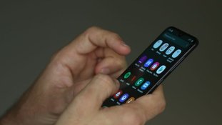Pessoa mexe no celular com as duas mãos