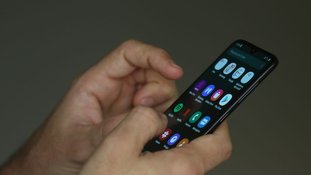 Pessoa mexe no celular com as duas mãos