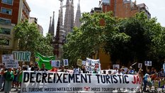 Pessoas seguem um cartaz com os dizeres "Reduzam o turismo já" durante protesto contra o turismo em massa, em Barcelona, Espanha. 15/06/2025