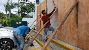 Pessoas colocam tábuas de madeira contra um prédio como proteção, enquanto o furacão Erick se fortalece na costa do Pacífico do México, em Acapulco, estado de Guerrero, México, em 18 de junho de 2025