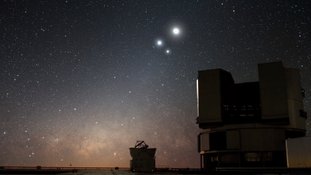 No céu noturno sobre o observatório do Very Large Telescope (VLT), do ESO, no Paranal (Chile), a Lua brilha juntamente com dois objetos brilhantes: no centro da imagem, está Vênus, o vizinho planetário mais próximo da Terra, e, à sua direita, o planeta gigante, embora mais distante, Júpiter. Essas aparentes quase colisões celestes — embora os corpos celestes estejam, na verdade, a dezenas ou centenas de milhões de quilômetros de distância — são chamadas de conjunções