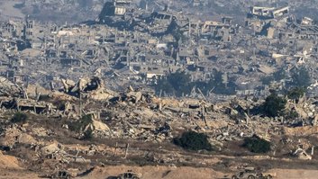 Foto a partir do sul de Israel mostra veículos militares israelenses e prédios destruídos na Faixa de Gaza, em 6 de julho de 2025 - AFP