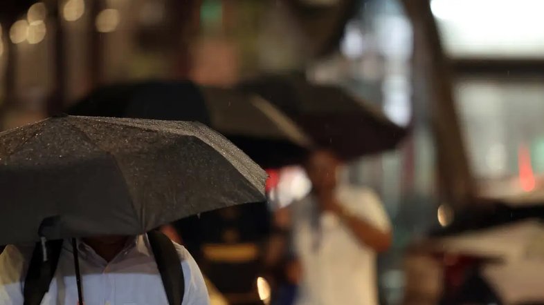Fotografia de pessoas a caminhar com guarda chuvas