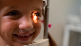 Criança tem o olho examinado por oftalmologista