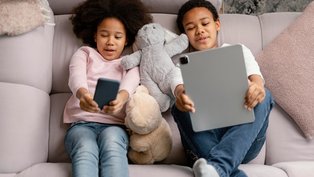 Irmãos entretidos com celular e tablet