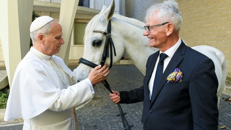 Papa Leão XIV (à esquerda) recebendo Proton, um cavalo puro-sangue árabe branco, das mãos do polonês Andrzej Michalski (à direita - VATICAN MEDIA/AFP