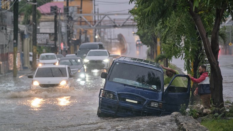 Pessoas abandonam um carro em uma rua intransitável inundada pelas chuvas causadas pela tempestade tropical Melissa em Santo Domingo, República Dominicana, sexta-feira, 24 de outubro de 2025