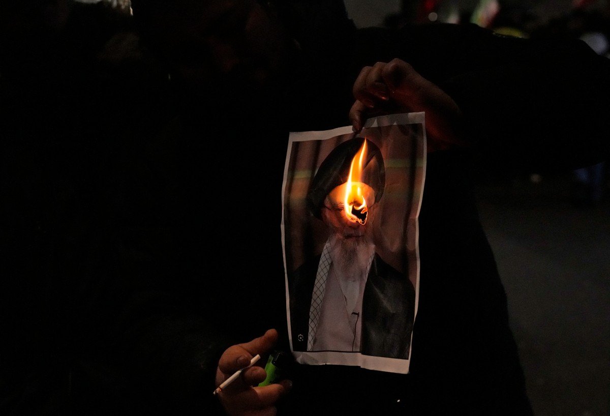 Manifestante queima imagem do aiatolá Ali Khamenei em ato no centro de Londres, neste domingo, 1 de janeiro de 2026.