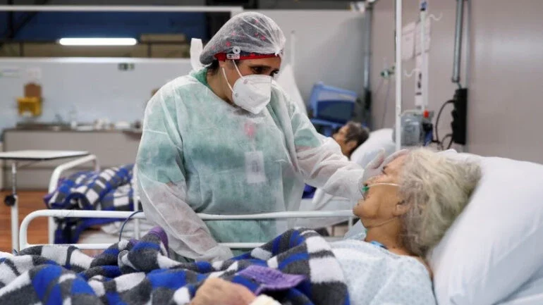 Enfermeira de um hospital em Santo André, no Estado de São Paulo, conversa com paciente idosa