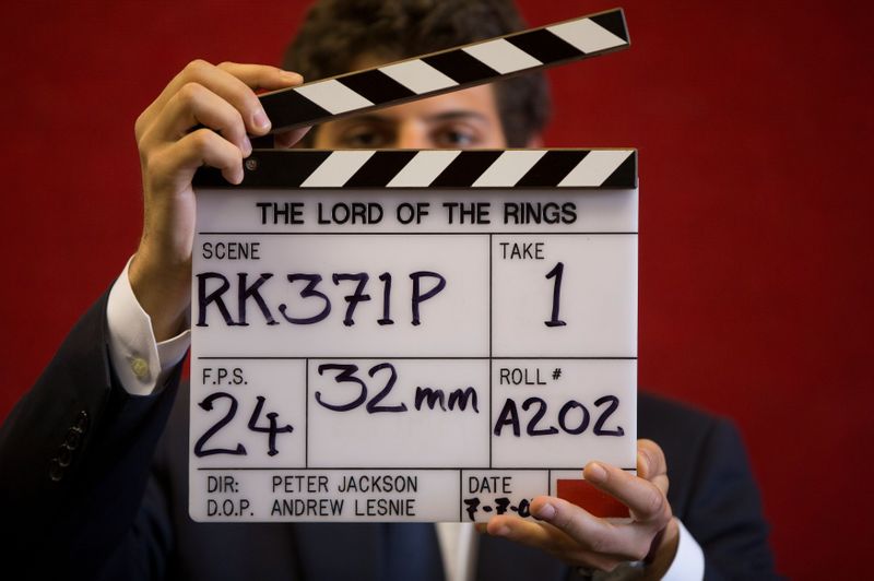 Assistente de galeria posa com claquete durante filmagem de "O Senhor dos Anéis" em casa de leilões de Londres
