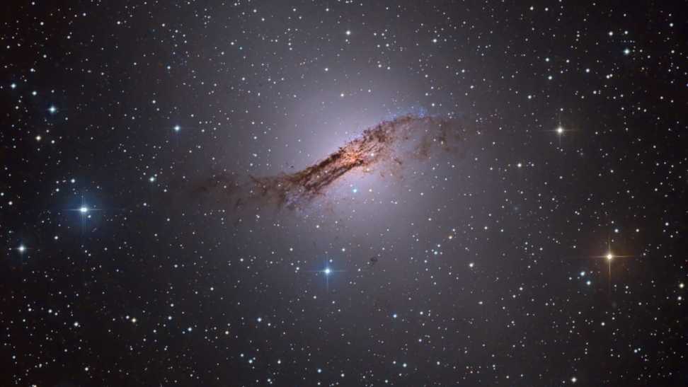 A apenas 11 milhões de anos-luz de distância, Centauro A é a galáxia ativa mais próxima do planeta Terra. Abrangendo mais de 60 mil anos-luz, a peculiar galáxia elíptica, também conhecida como NGC 5128, é apresentada nesta visão telescópica nítida. Perto do centro da galáxia, restos cósmicos estão sendo constantemente consumidos por um buraco negro com um bilhão de vezes a massa do Sol. Como em outras galáxias ativas, esse processo provavelmente gera a enorme energia de rádio, raios X e raios gama irradiada por Centauro A